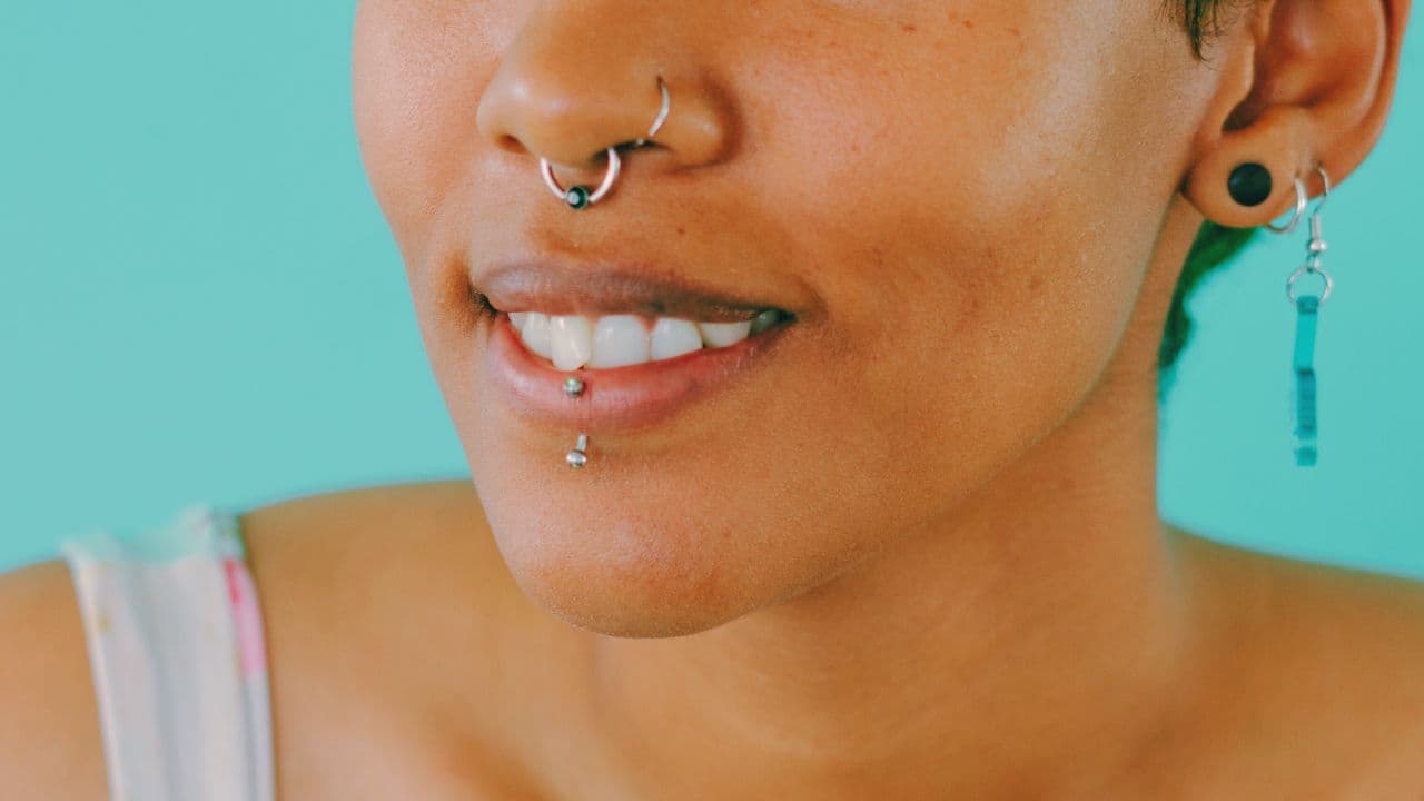 mulher com Piercing no nariz, boca e orelha.