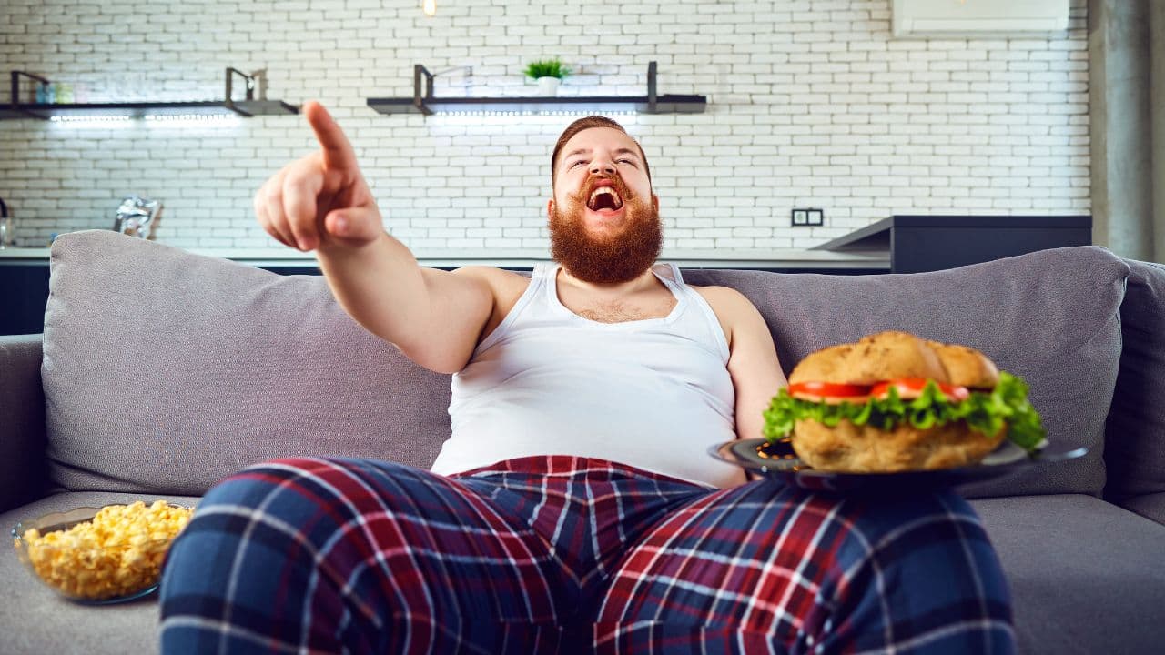 homem guloso com hambúrguer grande na mão.