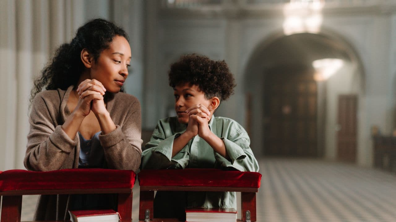 mãe orando mais o filho na igreja.