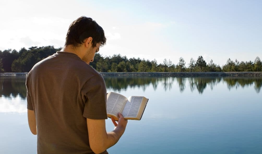 cristão lendo a bíblia a beira do lago.